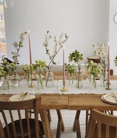 the table is set with many vases and flowers on it, along with candles