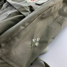 a close up of a jacket with flowers on the front and side pockets, sitting on a white surface