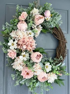 a wreath with pink and white flowers hanging on a door