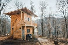 a small wooden cabin in the woods with stairs leading up to it's roof