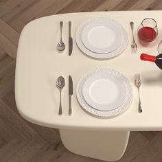 a white table topped with plates and silverware next to a red wine bottle on top of a wooden floor