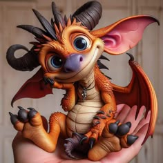 a toy dragon sitting on top of someone's hand