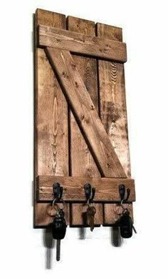 a wooden wall mounted coat rack with three hooks and two keys hanging from it's sides