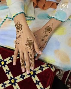 a woman's hands with henna tattoos on her left hand and the bottom half of her arm