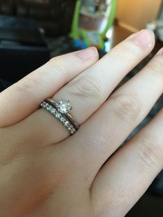 a woman's hand with two wedding rings on top of her finger and the other ring