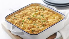 a casserole dish with meat and vegetables in it on a wooden cutting board