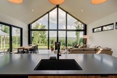 a kitchen island in front of a living room and dining area with large glass windows