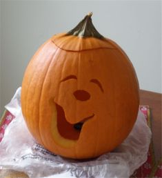 a pumpkin carved to look like winnie the pooh sitting on top of plastic wrap