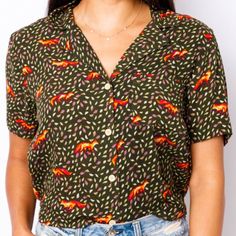 Dark Green Shirt With Roaming Foxes Among Small Tan And Purple Leaves In The Background - Short Waisted - Elastic Waistband In Back - Chest Pocket - Rayon Approx Length - 20" Orange Tops With Button Closure For Work, Orange Short Sleeve Top With Buttons, Green Camp Collar Shirt, Orange Button-up Summer Top, Summer Orange Button-up Top, Orange Collared Top With Button Closure, Orange Button-up Tops For Summer, Casual Orange Collared Camp Shirt, Orange Collared Top With Buttons