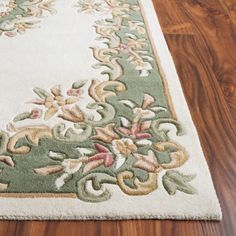 a white rug with green and pink flowers on top of wooden floor next to hardwood floors