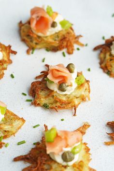 small appetizers are arranged on top of each other, including salmon and capers