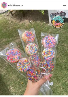 a person holding up some doughnuts with sprinkles on them in plastic bags