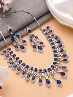 Add a touch of glamour and sophistication with this high quality necklace set in beautiful  sapphire blue stones. The stones in this set bling and look close to the real thing. This set is sure to make heads turn!  It features an adjustable necklace and a pair of earrings. It can be paired perfectly with both ethnic and western outfits.  In case of any queries, please feel free to reach out. Happy shopping! Necklace weight: 70 gms Length :16 inches Adjustable length with a metal chain at the bac Blue Formal Jewelry With Stones, Formal Blue Jewelry With Stones, Formal Blue Stone Jewelry, Sapphire Crystal Jewelry For Anniversary, Blue Cubic Zirconia Jewelry For Party, Blue Cubic Zirconia Party Jewelry, Elegant Blue Bridal Sets Gift, Blue Fine Jewelry Sets For Anniversary, Blue Hand Set Jewelry Sets For Wedding