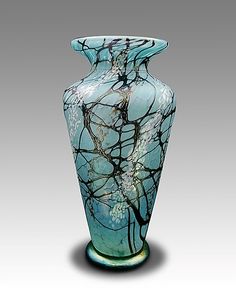 a glass vase with blue and white designs on the bottom, sitting in front of a gray background