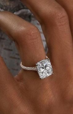 a woman's hand with a diamond engagement ring on her left hand, and the middle