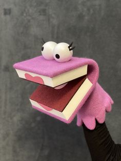 a hand holding two books with eyes and nose sticking out of it's covers