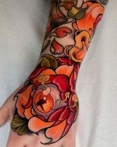 a hand with an orange flower tattoo on it