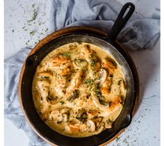 a skillet filled with pasta covered in cheese and sauce on top of a blue towel