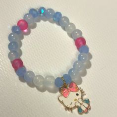 a hello kitty bracelet with pink, blue and white beads is displayed on a table