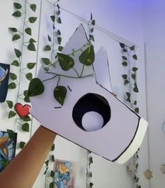 a person holding up a paper cut out of a cat head with plants growing on it