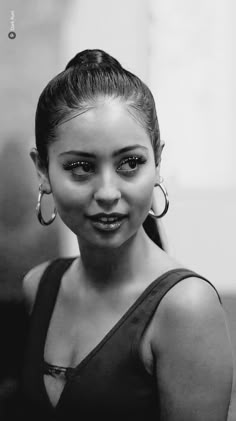 a black and white photo of a woman with large hoop earrings on her head, smiling