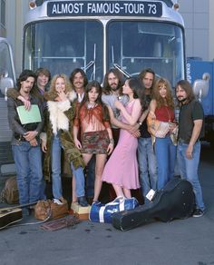 a group of people standing in front of a bus with their arms around each other