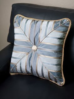 a blue pillow sitting on top of a black couch next to a white and gold wall