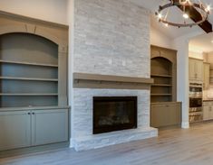 an empty living room with a fireplace and built in cabinets