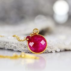 Back in stock! This striking Ruby necklace looks rich and exotic, and is perfect for adding colour to any outfit or occasion. Featuring a sparkling, round, cut and faceted ruby set in a bezel setting and paired with a dangling ruby gem. Available in various lengths. Rubies are the birthstone for July and the 40th wedding anniversary. Ruby jewelry makes a perfect romantic gift for a loved one, whether for a birthday, anniversary or Valentine's Day, as Rubies have always been associated with love Spiritual Gemstone Necklaces For Celebration, Red Faceted Pendant Necklaces, Red Faceted Pendant Necklace, Party Jewelry With Birthstone, Gemstone Necklace With Round Pendant For Celebration, Ruby Briolette Gemstone Jewelry, Red Faceted Round Necklaces, Red Faceted Round Necklace, Unique Faceted Necklaces