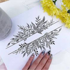 a woman's hand on top of a piece of paper next to yellow flowers