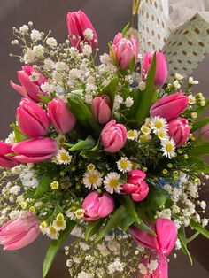 a bouquet of pink tulips and white daisies in a clear glass vase