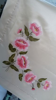 pink flowers are embroidered onto the side of a white pillow case with stitching on it