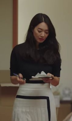 a woman in a black top and white skirt holding a plate