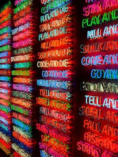 neon signs are lit up on the wall in front of them with words written all over it