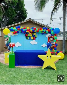 an outdoor birthday party setup with balloons, stars and mario bros balloon arch on the lawn