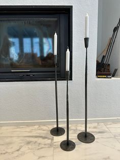 two candles are standing next to each other in front of a fireplace