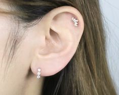 a close up of a person's ear with three small diamond studs on it