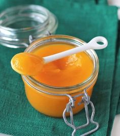 an orange jam in a glass jar with a spoon