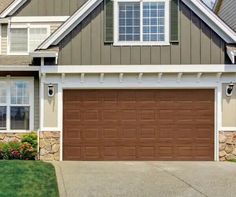 a brown garage door in front of a gray house with white trim on the windows