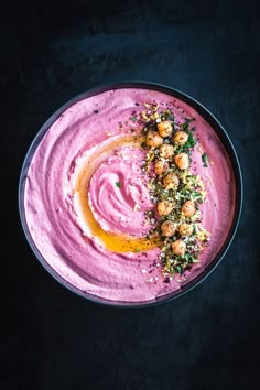 a bowl filled with pink hummus and garnished with parsley