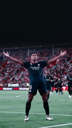 a man standing on top of a soccer field holding his arms up in the air