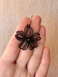 a hand holding a piece of black wire with a flower on it's end