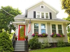 a house with flowers in the window boxes and an american flag on the front door