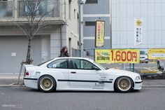 a white car parked on the side of a road next to a tall building with yellow lettering