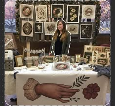 a woman standing in front of a table with pictures on it