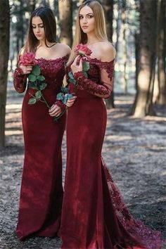 two women in long dresses standing next to each other with roses on their chests