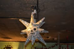 a crystal star ornament hanging from a ceiling in a room with lights and decorations