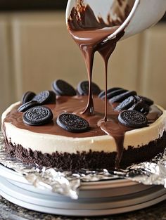 someone is drizzling chocolate on top of a oreo cookie cheesecake