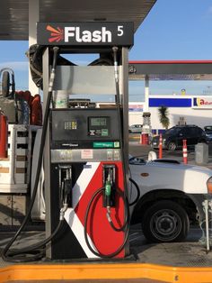 a white truck is parked next to a gas station with a red and black sign that says flash 5