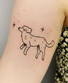 a woman's arm with a small tattoo of a dog and stars on it